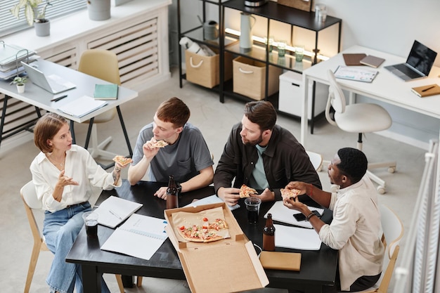 Leute, die während des Unternehmens im Büro Pizza essen