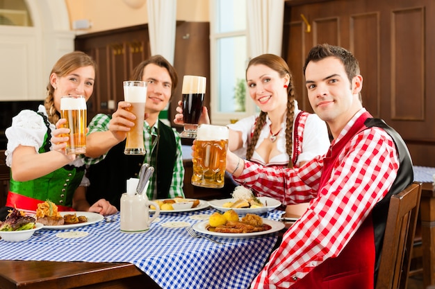 Leute im traditionellen bayerischen Tracht, das im Restaurant oder in der Kneipe isst