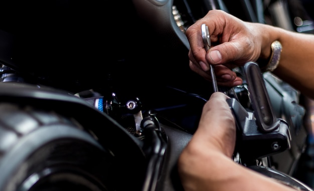 Leute reparieren ein Motorrad Verwenden Sie einen Schraubenschlüssel und einen Schraubenzieher, um zu arbeiten.