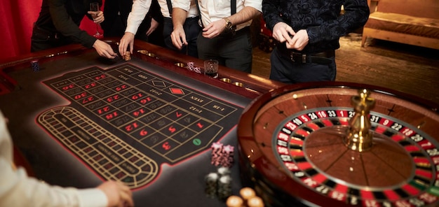 Leute spielen Schürhakenroulette am Tisch Freunde, die im Kasino spielen Kasino-Roulette
