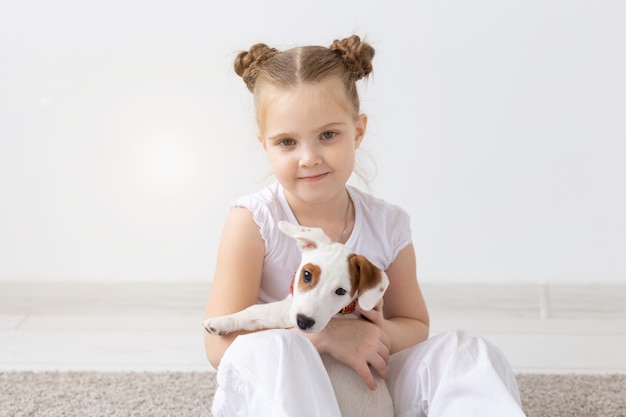 Leutehaustiere und Tierkonzept kleines Mädchen, das auf dem Boden über weißem Hintergrund sitzt und hält