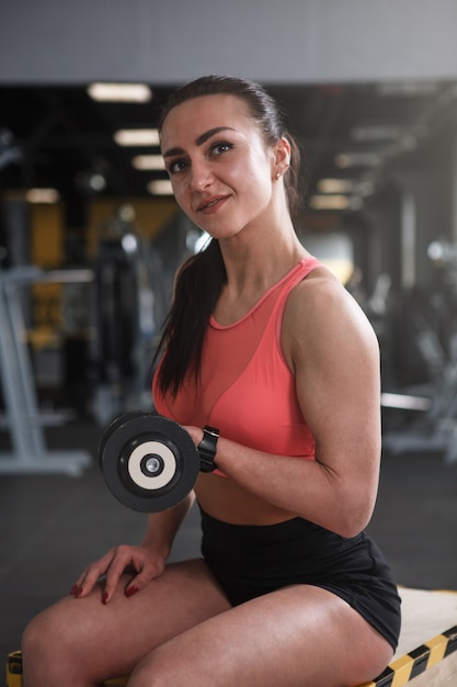 Foto levantadora de peso feminina alegre se exercitando com halteres na academia