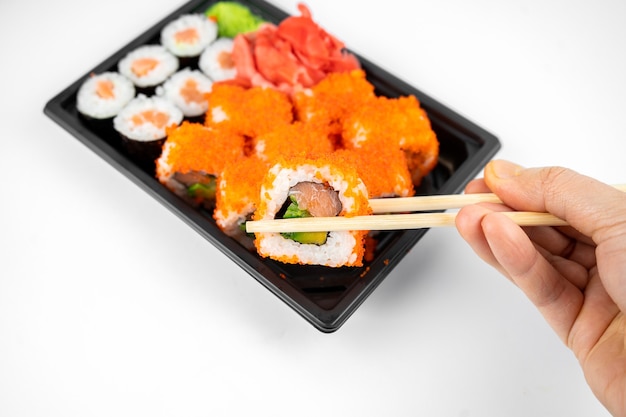 Leve os rolos de sushi em um recipiente de plástico, califórnia, rolo de maki de salmão, gengibre rosa, wasabi. conceito de entrega de sushi