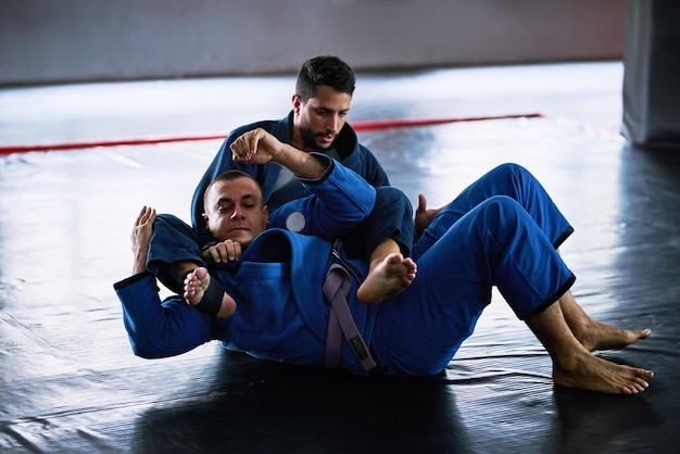 Foto leve para o tapete foto de corpo inteiro de dois jovens atletas treinando no chão de seu dojo