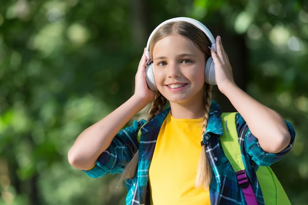 Leve seus fones de ouvido aonde quer que vá Criança feliz Use fones de ouvido naturais ao ar livre Ouvindo música Diversão e entretenimento Nova tecnologia Férias de verão Faça dos fones de ouvido seus melhores amigos