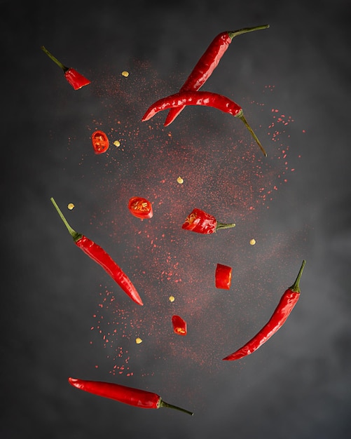 Levitação de pimenta vermelha inteira e fatias com páprica em pó contra um fundo preto