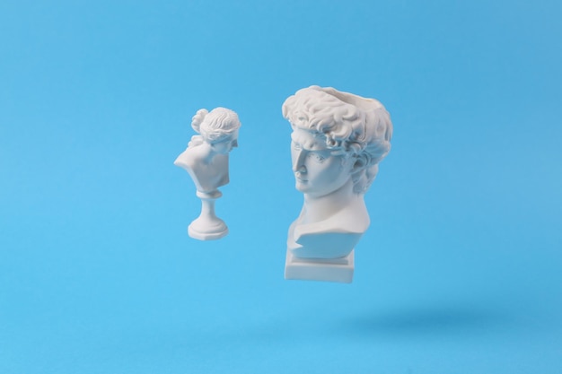 Levitación Antiguo Bustos de yeso de David y Venus sobre fondo azul con sombra Pop conceptual Fotografía minimalista de naturaleza muerta