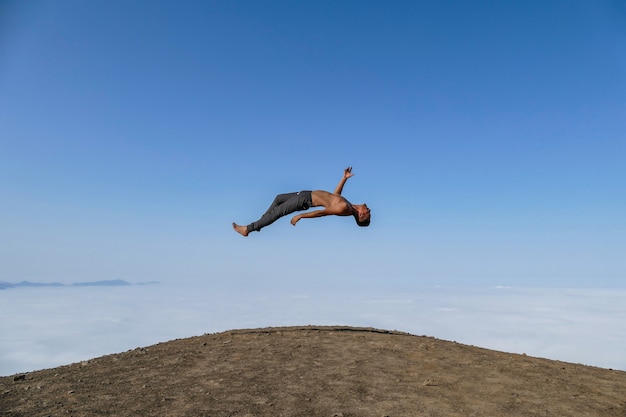 levitando homem em uma colina de céu azul e fundo de nuvens