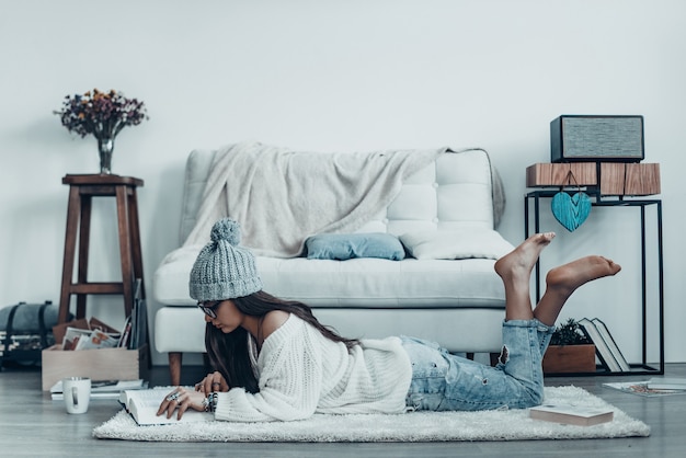 Leyendo una historia interesante. Hermosa mujer joven en ropa casual y libro de lectura de sombrero de punto