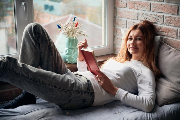 Leyendo un libro en la zona de estar junto a la ventana