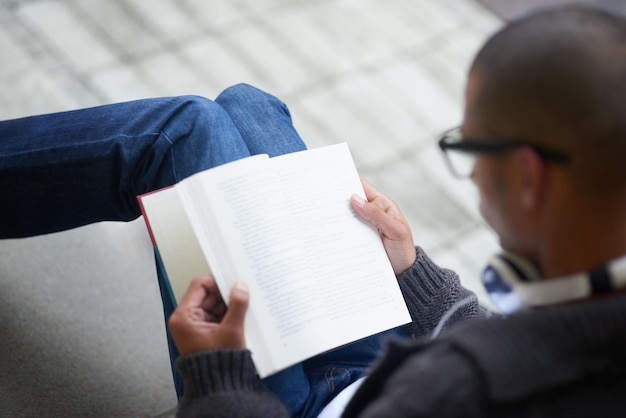 Leyendo notas para su próxima conferencia Captura recortada de un estudiante universitario leyendo un libro mientras está sentado afuera en el campus