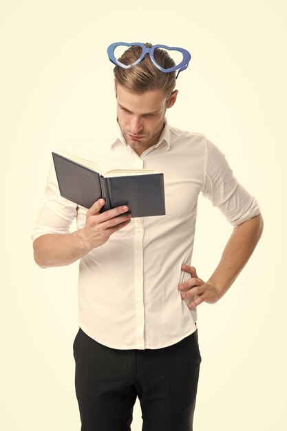 Leyendo poesía Hombre guapo joven buscando poesía agradable Cara ocupada de hombre en anteojos en forma de corazón leyendo libro Chico encontró poesía en libro aislado fondo blanco Libro de lectura concentrado