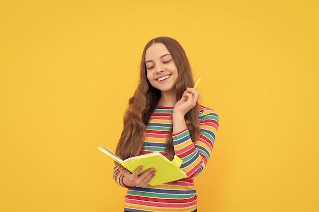 Leyendo su ensayo escolar Niña feliz sostiene pluma y cuaderno Tarea de ensayo Redacción de ensayos Escribir historia