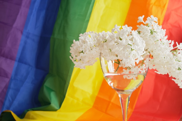 LGBT-Regenbogenband und ein Strauß weißer Flieder im Glas. Stolzes Bandsymbol. Platz kopieren. Konzept der LGBT-Rechte.