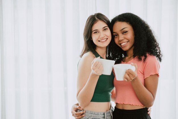 Foto lgbtq-schlanke frauen stehen zusammen mit weißen tassen und trinken kaffee oder tee