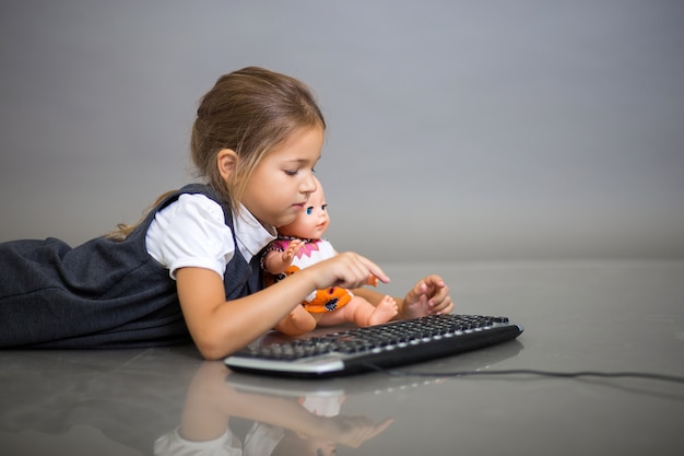 lgirl spielt mit der tastatur vom computer und einer puppe