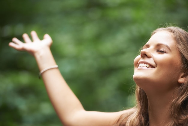 Liberdade de sorriso e braços de mulher levantados em uma floresta para saúde mental bem-estar ou meditação zen natureza de verão e um jovem feliz no campo para relaxar para a paz equilíbrio ou atenção plena