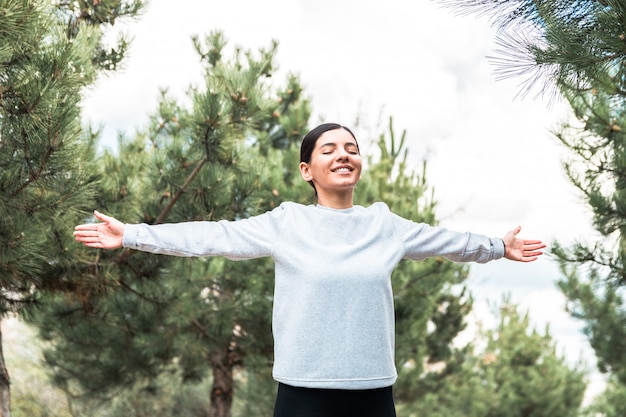 Foto libertad del alma y del cuerpo. mujer atractiva con los brazos abiertos y los ojos cerrados meditando y entendiendo que está en la naturaleza al amanecer