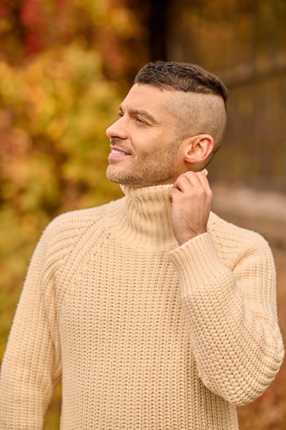 Libertad. Un hombre con un jersey de cuello alto beige en el parque de otoño