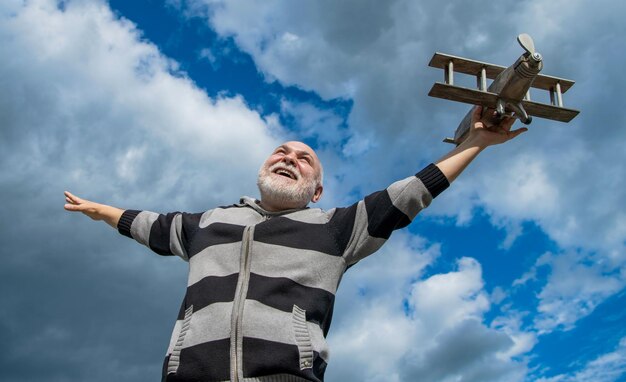 Libertad del hombre mayor en el fondo del cielo hombre mayor en la jubilación hombre jubilado mayor con avión de juguete