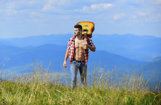 Libertad hombre vaquero feliz y libre con torso musculoso desnudo guitarrista acústico canción de música country hombre sexy con guitarra en camisa a cuadros hipster moda occidental camping y senderismo