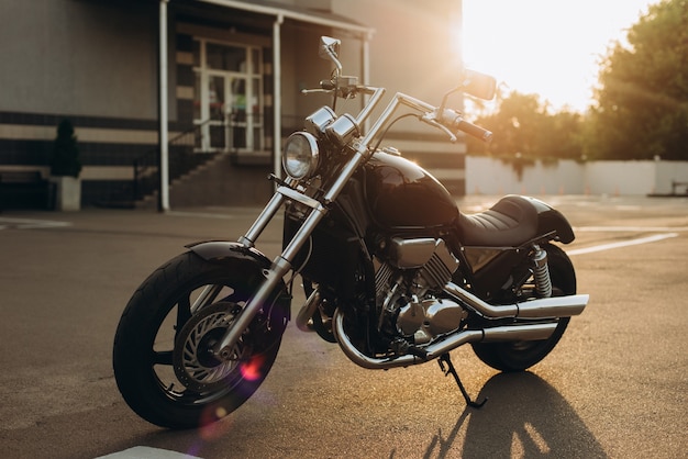 Libertad. Motocicleta en el estacionamiento en los rayos de la luz del atardecer. Elegante moto chopper personalizada con detalles cromados. Enfoque selectivo suave.