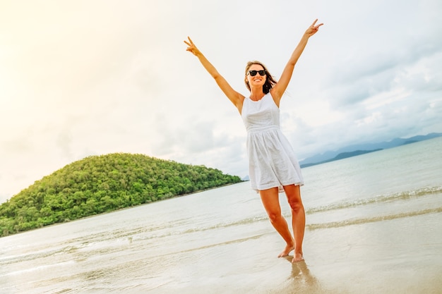 Libertad mujer feliz con los brazos levantados en la playa en día soleado