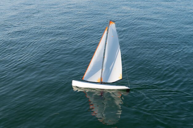 Libertad de navegación. Yate de juguete navega en el mar. Barco de juguete de vela en la superficie del mar. Navegación y vela. Modelo de nave.