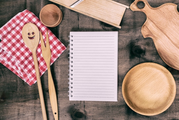 Libreta abierta con objetos de cocina de madera.