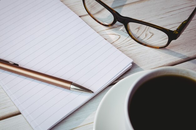 Libreta vacía con gafas y taza de café