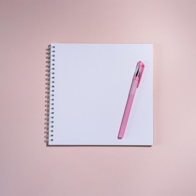 Libro abierto y bolígrafo sobre el fondo rosa.