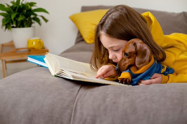 libro abierto está acostado en la cama, el niño juega en la escuela y le enseña al perro a leer Foto de alta calidad