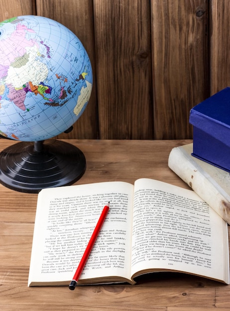 Foto un libro abierto con un globo terráqueo sobre una mesa.