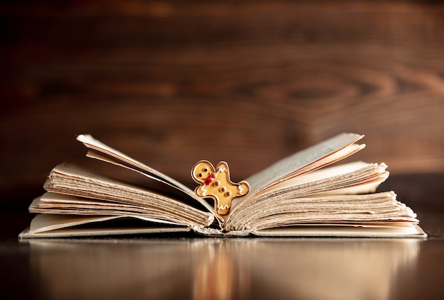 Libro abierto y hombre de jengibre en mesa de madera