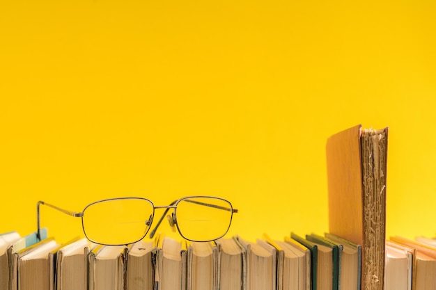 Libro abierto, libros de tapa dura con gafas de lectura en el lateral.