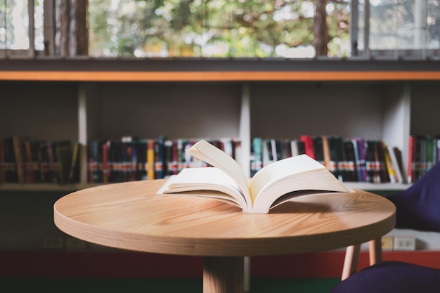 Un libro abierto o un libro de texto en la biblioteca con luz de la ventana en la mesa de lectura