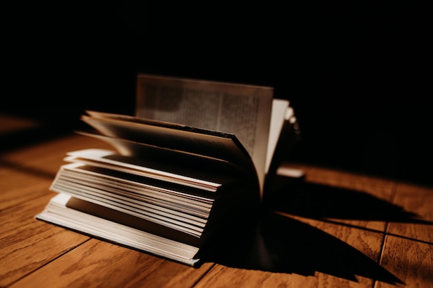 Libro abierto sobre una mesa de madera bajo la luz natural del sol