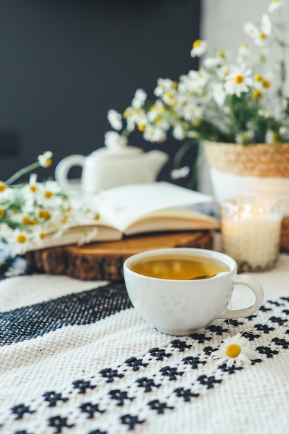 Libro abierto taza de té de manzanilla a base de hierbas en la lectura de la mesa de madera y concepto de relajación matutina