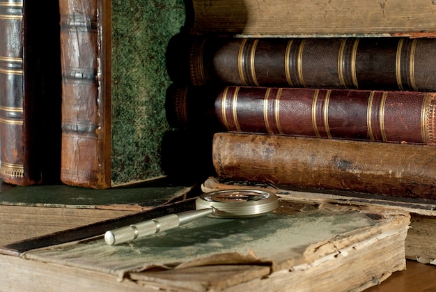 Foto un libro antiguo con una cubierta irregular y una lupa sobre una mesa.