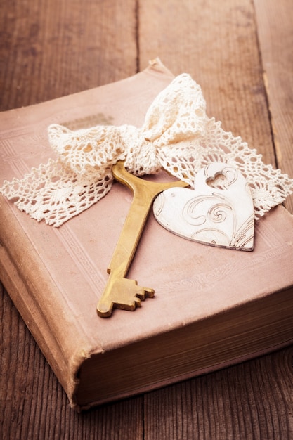 Foto libro antiguo con llave vintage y corazón de madera, concepto de recuerdos