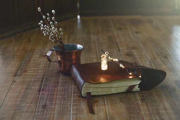 Libro antiguo y ramitas de sauce se encuentran en una mesa de madera closeup