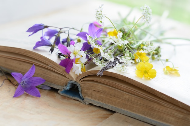 Libro antiguo con ramo de flores de pradera, superficie nostálgica vintage