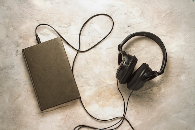 Libro y auriculares conectados a él en una piedra blanca