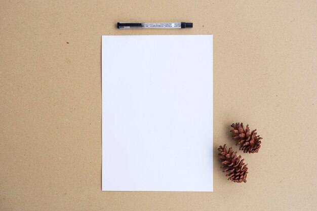 Foto libro blanco, flores de pino y lápiz sobre papel marrón. estilo minimalista