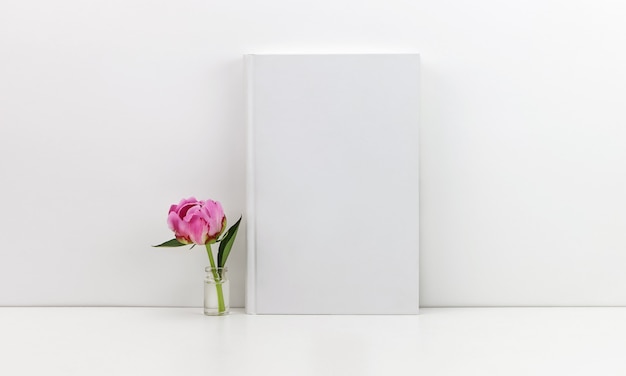 Foto libro blanco con una peonía rosa