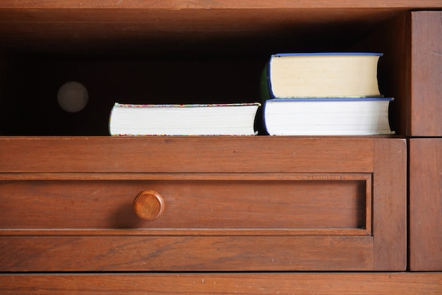 Libro de bolsillo en el estante del gabinete de madera con fondo oscuro en blanco vacío