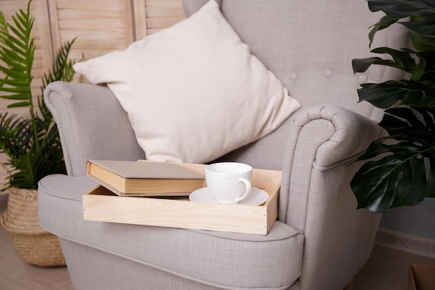 Libro de concepto de lectura con taza en sillón