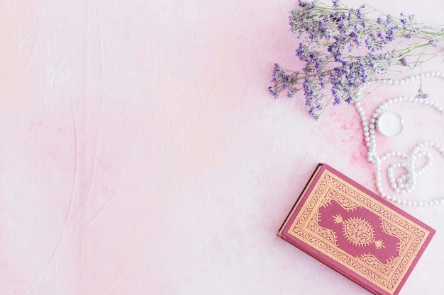 Foto libro del corán con pequeñas flores de color púrpura