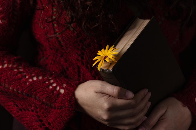Un libro con una flor como marcador en las manos del lector