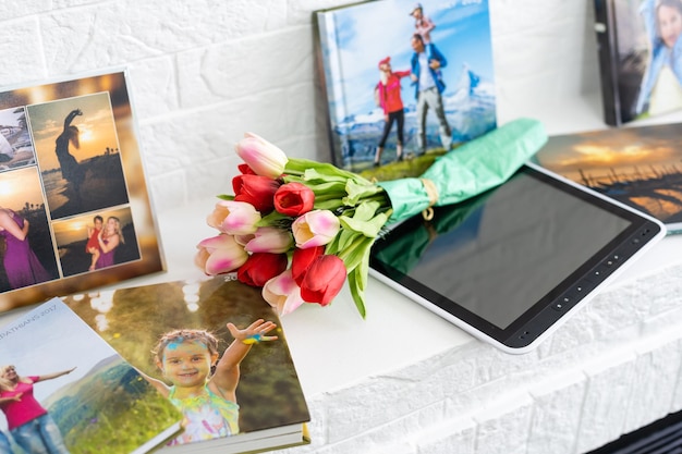 el libro de fotos y los tulipanes de flores como regalo de vacaciones se encuentran en el estante.